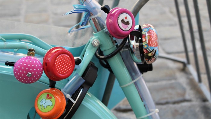 Teil eines türkis farbigen Fahrrads mit vielen bunten Klingeln