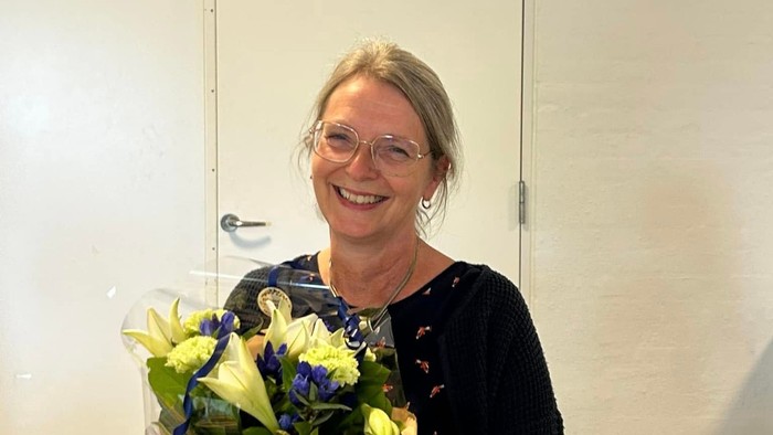 Nydelig midaldrende dame siddende storsmilende med blomsterbuket.