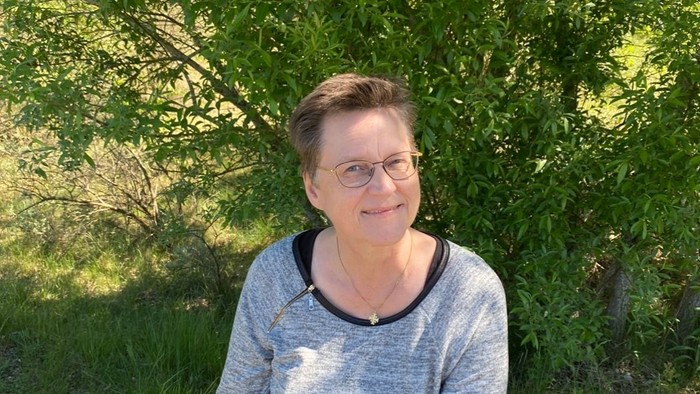 En kvinde sidder på en træstamme i skoven.