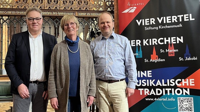 Drei Menschen stehen vor dem Plakat der 4Viertel Stiftung.