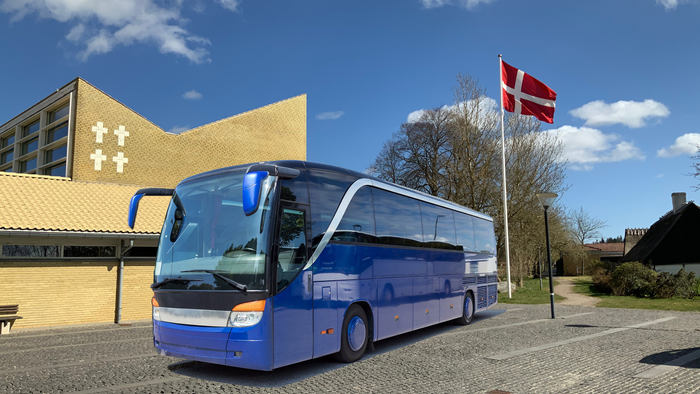 Blå turistbus stander ved kirke med dansk flag.