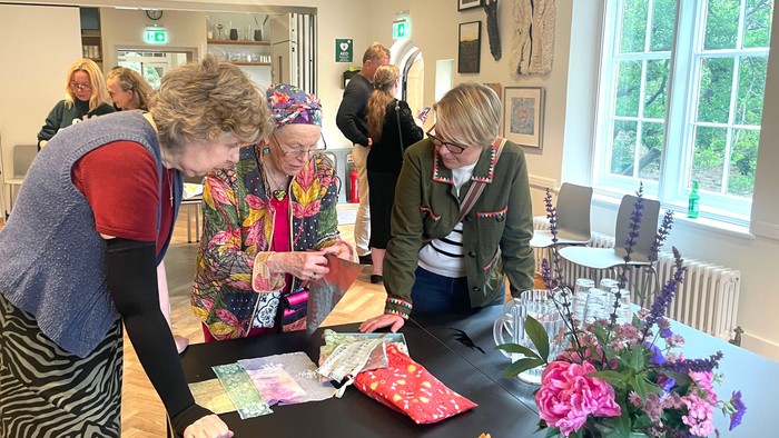 Gruppe af mennesker, der laver farverige dekorationer til et fællesskabsarrangement med blomsterarrangementer i baggrunden.