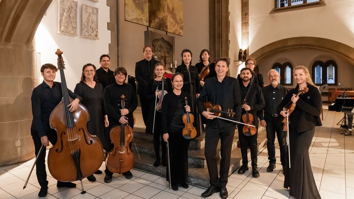 Musiker posieren mit ihren Instrumenten in einem prächtigen Saal.
