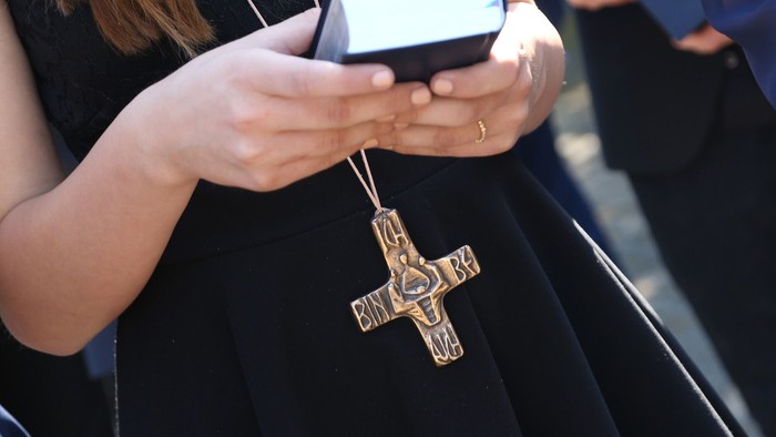 Konfirmandin mit Kreuz hält ein Gesangbuch.