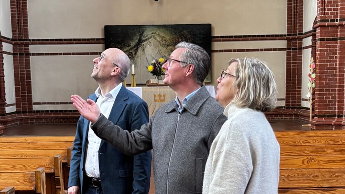 Drei Menschen schauen in unserer Kirche nach oben.