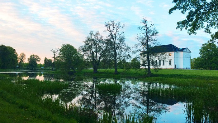 En stor, hvid bygning ved en sø i en park