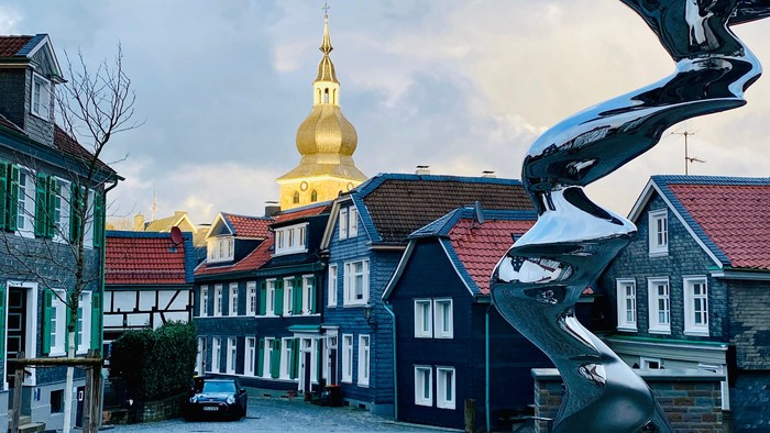 Modern Skulptur vor malerischem Dorfplatz mit Kirche