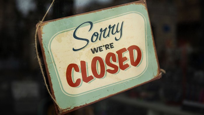 Vintage-Schild mit der Aufschrift *„Sorry we're closed“* in fetten, verwitterten Buchstaben.
