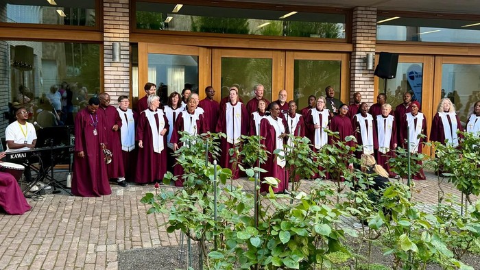Rund 30 Sängerinnen und Sänger in roten Roben in einem Innenhof
