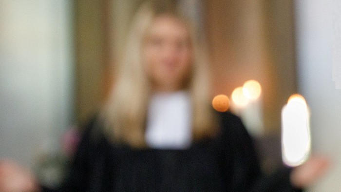 Eine Person mit blondem Haar hält ein Telefon und eine Zigarette.