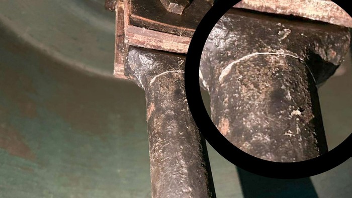 Ein Glockelklöppel mit einer Detailaufnahme eines beschädigten Teilstücks
