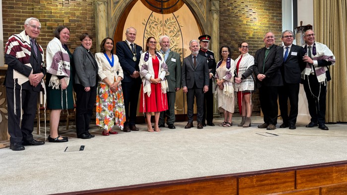 Group of formally dressed individuals posing together at a ceremonial event inside a grand hall.
