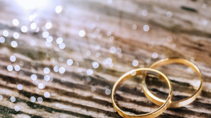 Zwei goldene Ringe auf Holz mit Sonnenlicht