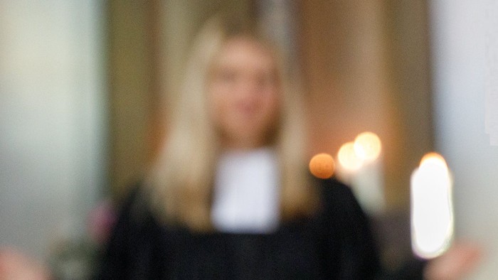 Eine Person mit blondem Haar hält ein Telefon und eine Zigarette.