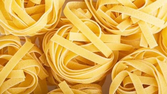 Gulde pasta bander ligger sammen i en haug.