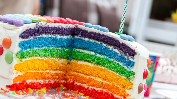 Bunter Regenbogen-Kuchen mit einer Kerze