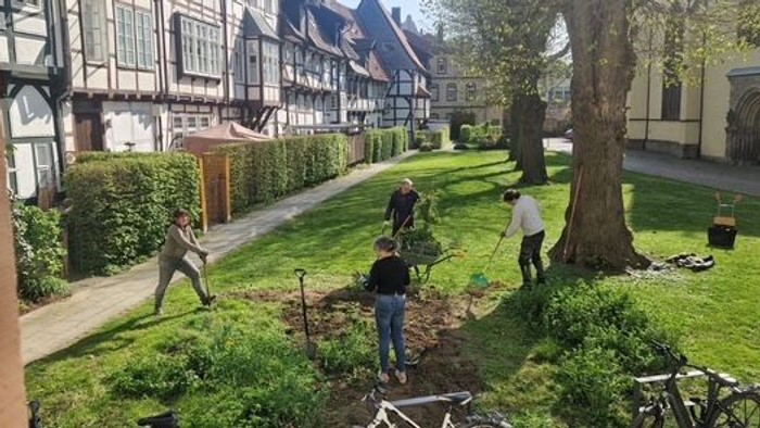 4 Leute machen Gartenarbeit hinter der Kirche