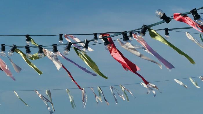 Bunte Bänder, die an einem klaren blauen Himmel vor einem Draht flattern.
