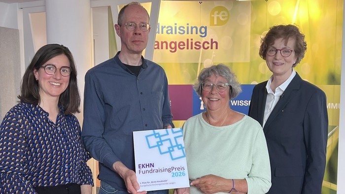 Vier Personen posieren mit einem Preis der EKHN-Fundraising-Auszeichnung 2020 und lächeln gemeinsam bei einer Veranstaltung.