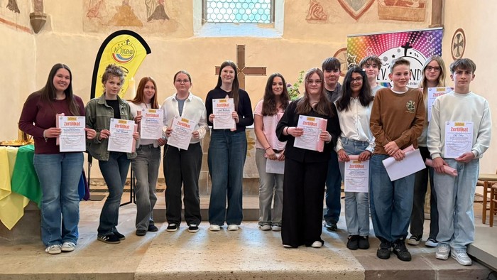 Gruppe von Studierenden, die in einer Kirche bei einer Preisverleihung Urkunden halten.