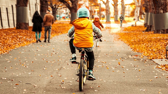 Ein Kind auf einem Fahrrad im Herbst, von hinten gesehen