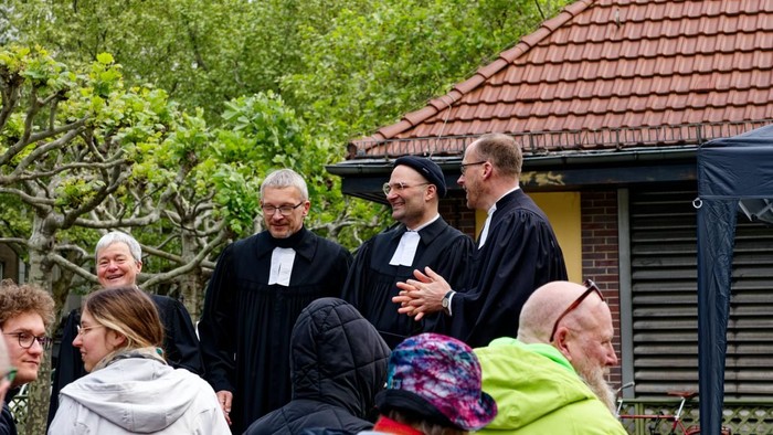 zu sehen sind alle vier Pfarrpersonen aus dem Pfarrsprengel beim Open Air Gottesdienst auf dem Mierendorffplatz und davor ein paar Teilnehmende. 
