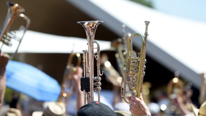 Nahaufnahme von Blaskapellen-Musikern, die während einer Aufführung im Freien Trompeten und Posaunen spielen.