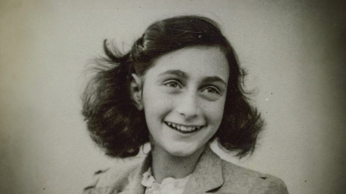 Junges Mädchen, das in einem Vintage-Porträt herzlich lächelt, mit schulterlangem Haar und einer geknöpften Jacke.