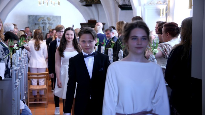 En gruppe børn i festlige klæder står i en kirke.