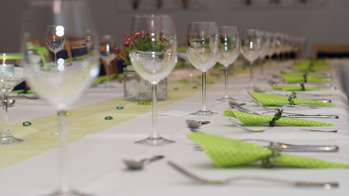 Ein festlich gedeckter Tisch mit grünen Servietten und Kristallgläsern
