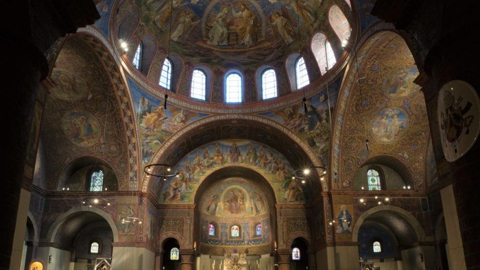 Komplexes byzantinisch geprägtes Kathedraleninneres mit lebendigen Mosaiken, Bögen und religiöser Ikonographie.