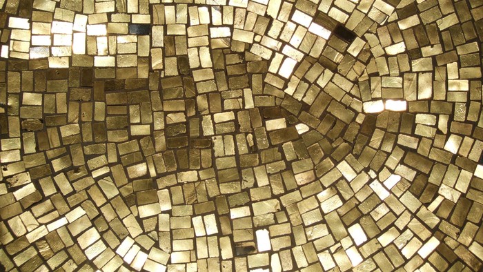 Komplexe goldene Mosaikfliesen in einem geschwungenen, geometrischen Muster angeordnet.