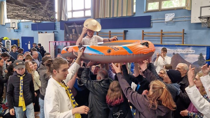 Jugendliche beim Katholikentag heben ein Schlauchboot über ihre Köpfe