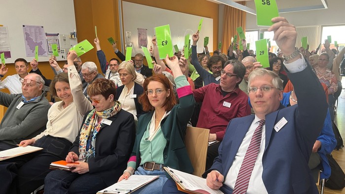 Foto von Synodalen bei der Abstimmung. Im Vordergrund u. a. Superintendent Christian Notmeier und seine Stellvertretenden