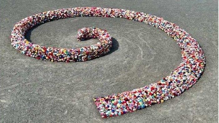 Bunte Perlen bilden ein kompliziertes Spiralmuster auf einer sandigen Oberfläche.