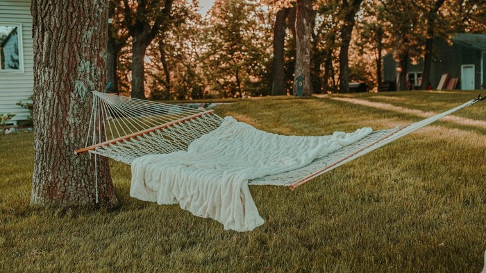 Eine Hängematte mit Decke in einem Garten bei Sonnenuntergang