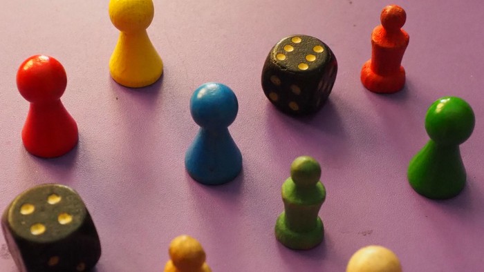 Bunte Spielsteine und Würfel auf lila Oberfläche