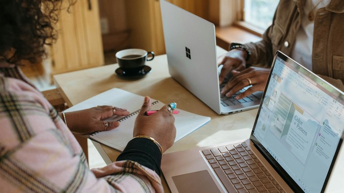 To folk arbejder på laptoper og noter i køkken.