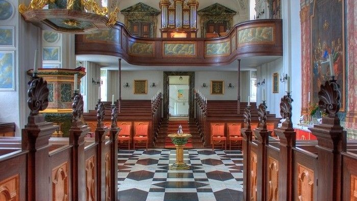 Indre del af prægtig kirke med høje bænke og indviklede detaljer.