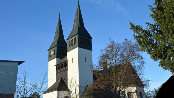 Eine historische Kirche mit Zwillingstürmen und Uhrturm vor einem klaren blauen Himmel.