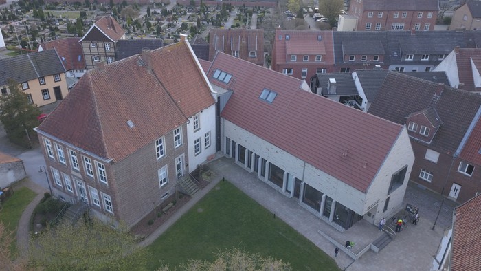 Ein großes Gebäude mit rotem Dach inmitten eines Wohngebiets.
