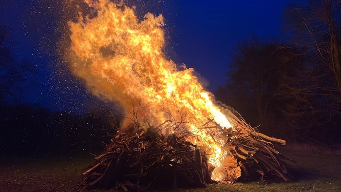 Lebendiges Lagerfeuer, das hell vor einem dunklen, sternenklaren Nachthimmel lodert.