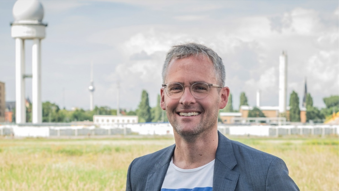 Ein Mann mit Brille und grauen Haaren steht auf dem Tempelhofer Feld.