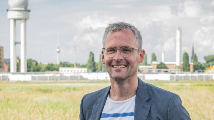 Ein Mann mit Brille und grauen Haaren steht auf dem Tempelhofer Feld.