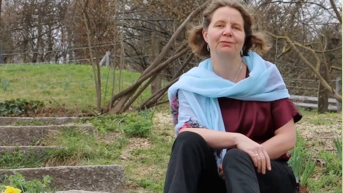 Pfarrerin Claudia Mieth auf einer Treppe in frühlingshafter Landschaft sitzend