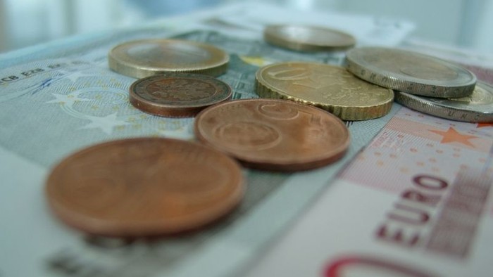 Einige Münzen und Euro-Scheine liegen auf einem Tisch