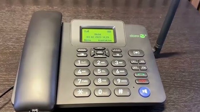En grå trådløs telefon, der viser et indgående opkald med store, letlæselige knapper og en grøn skærm.