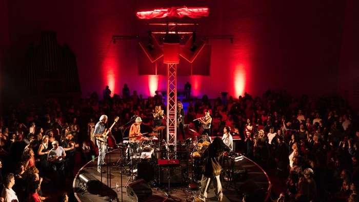 Runder Zuschauerraum in der Emmaus-Kirche. In der Mitte eine Band mit stimmungsvollem roten Licht