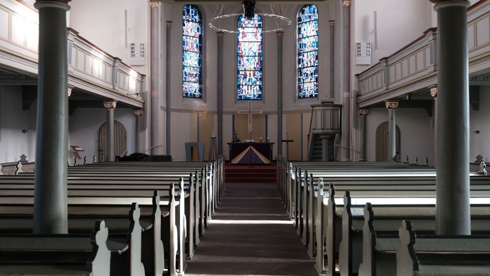 Innenraum einer Kirche mit hohen Säulen und bunten Glasfenstern