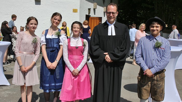 Die vier Konfirmanden mit Pfarrer Müller vor unserer Kirche.
